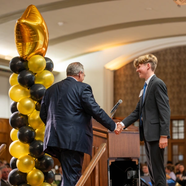Students shakes hand with executive