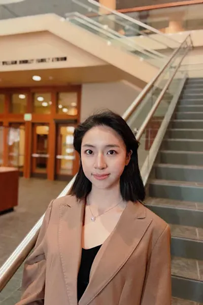 A young student standing in the stairway of the Daniels School of Business.