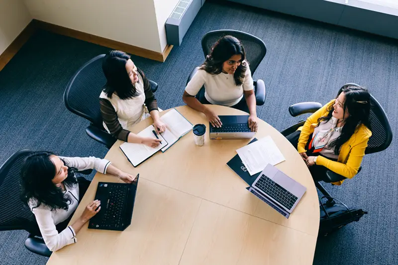 Four students sit around a table