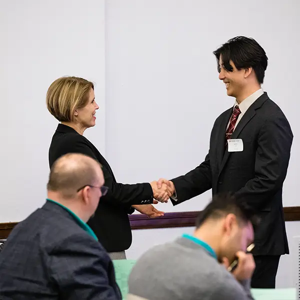 A student shakes hands with Professor Cara Putman