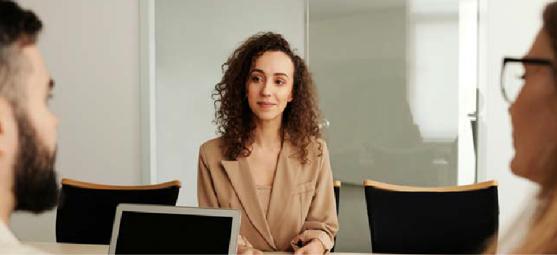 Woman at desk faces two employees