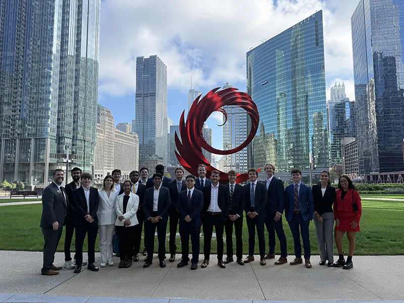 Group of tudents standing in front of a sculpture