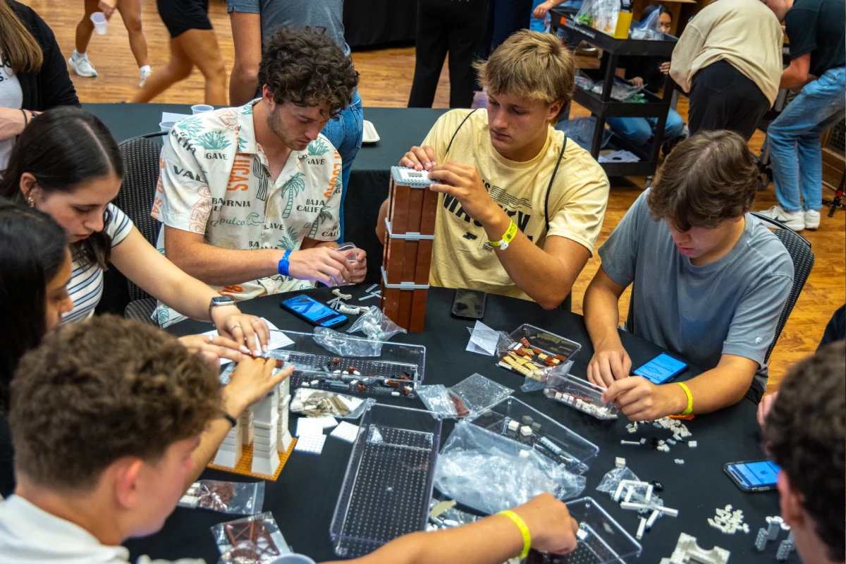 Group of students building the Bell Tower model at a table with LEGOs