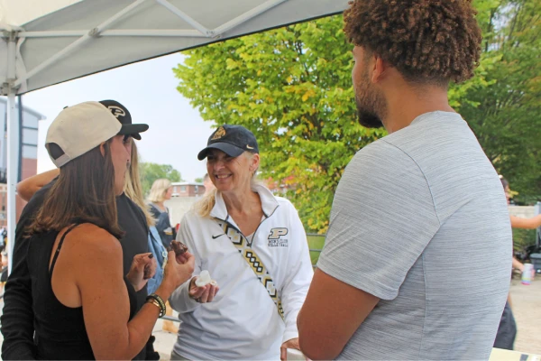 Woman wearing Purdue hat in conversation at tailgate event