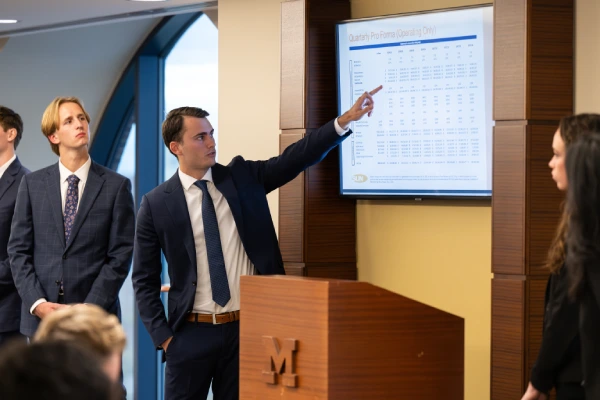 Group of tudents standing in front of a sculpture