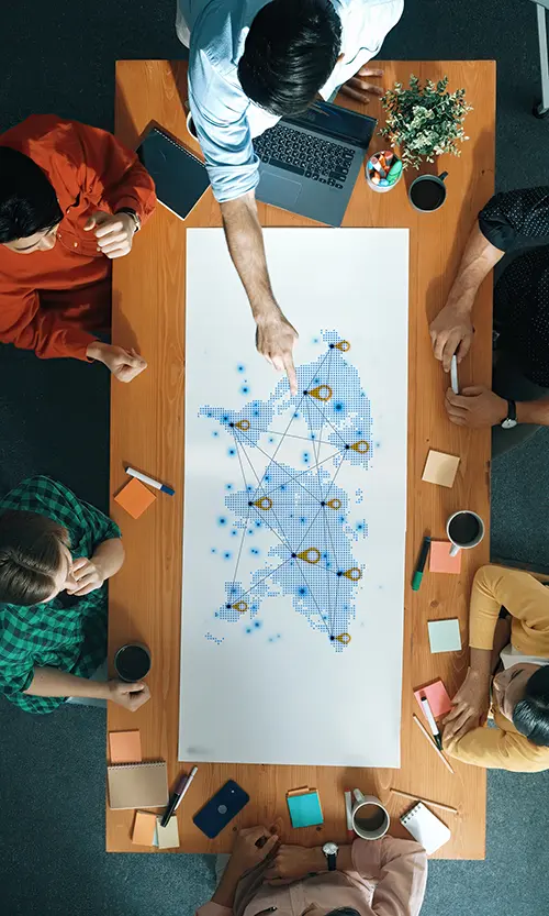 Stock image of six people around a table pointing at a digital map