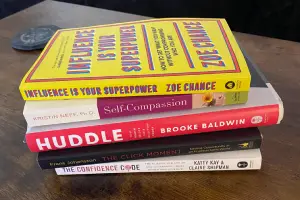 Pile of books given out to students to help with graduation: Influence is Your Superpower by Zoe Chance, Self-Compassion by Kristin Neff, Huddle by Brooke Baldwin, The Click Moment by Frans Johansson, and The Confidence Code by Katty Kay and Claire Shipman