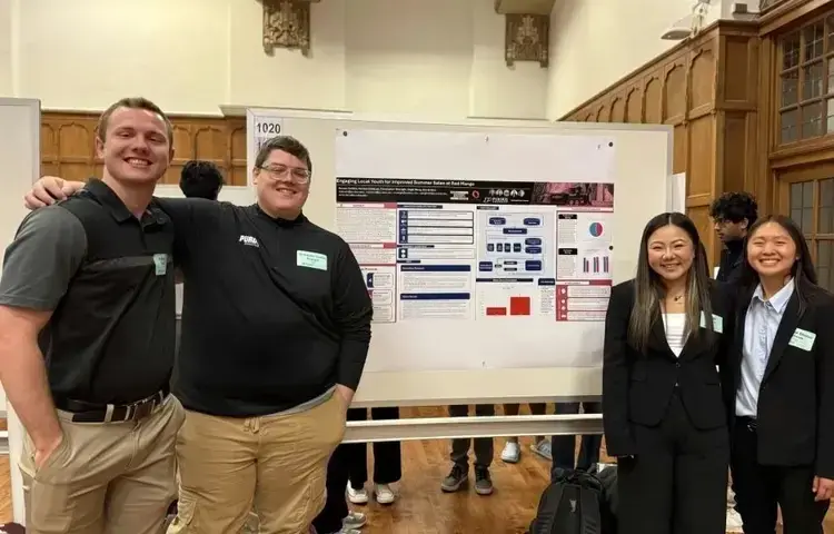Chris with his team standing in front of the poster made for his research project.