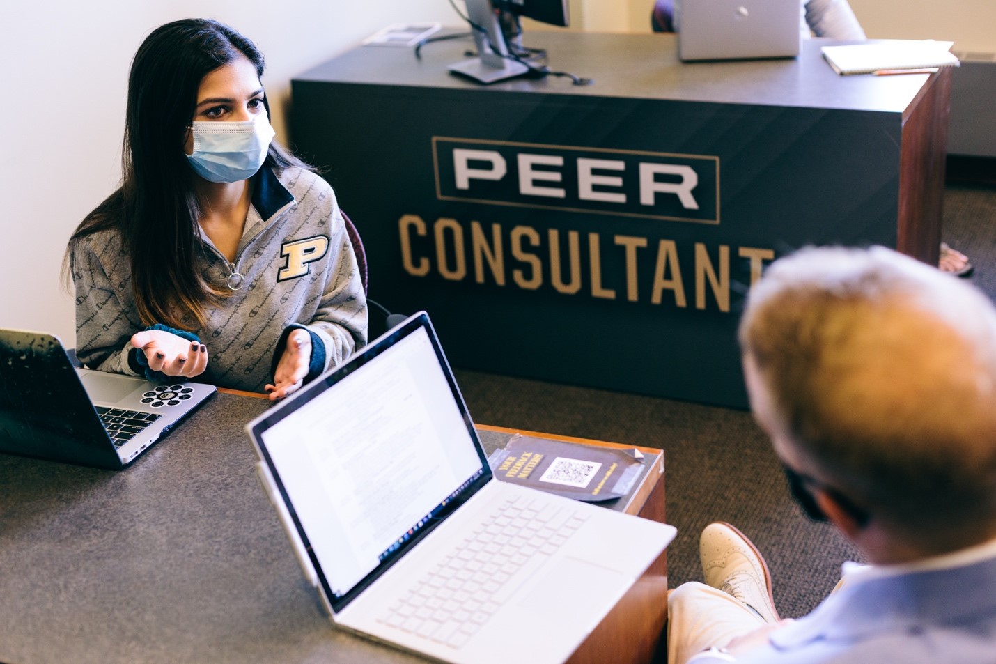 The author speaks with a student at her desk