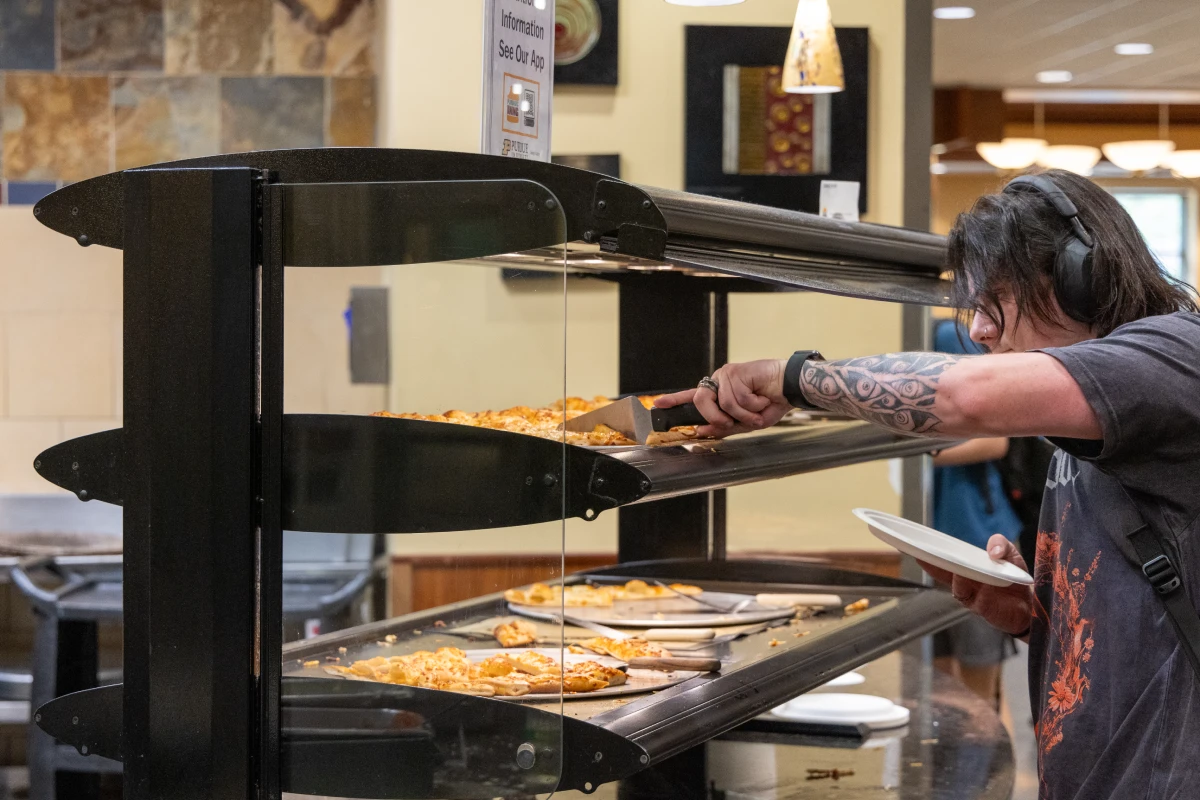 Student grabbing slice of pizza in food hall